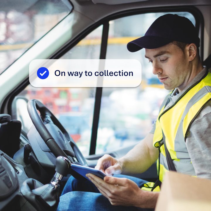 A delivery driver wearing a high vis jacket, siting in a van tapping on a mobile device. The image is overlayed with the notification 'On way to collection'