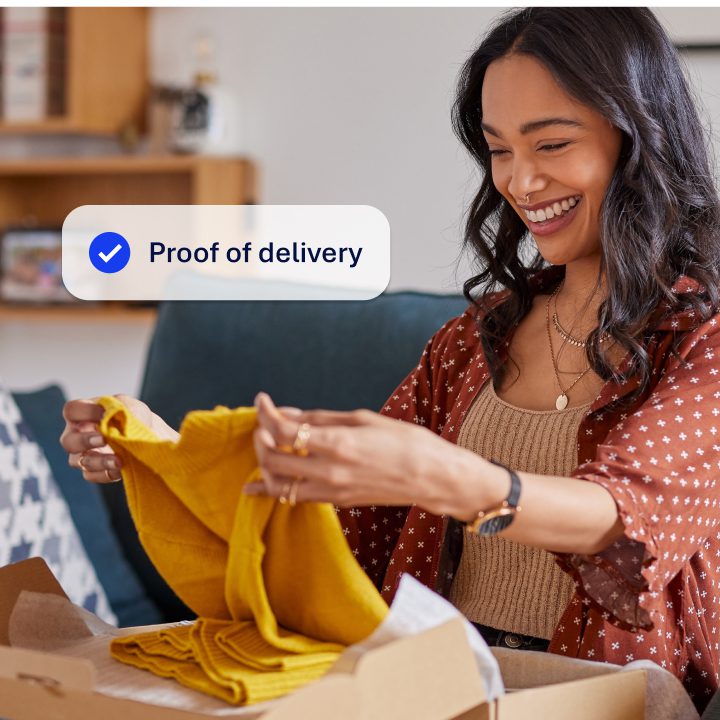 An image showing a women smiling as she opens a parcel with clothes ordered from an ecommerce website. Overlayed on the image is a notification saying 'Proof of Delivery'